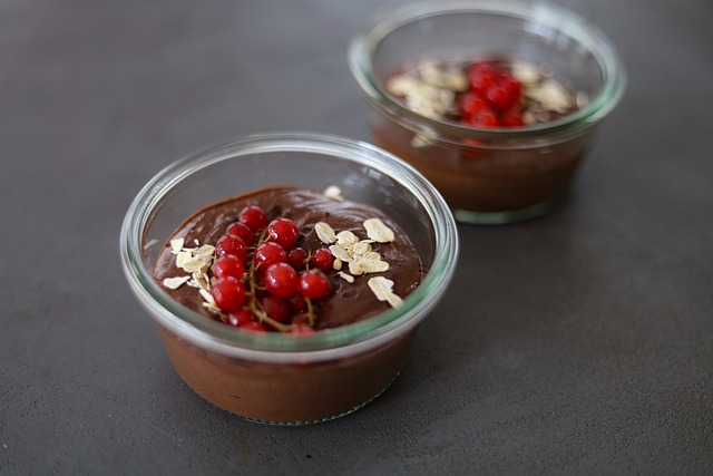 Čokoládový pudink je naservírován ve skleněných miskách, ozdoben je čerstvým rybízem a mandlovými lupínky.